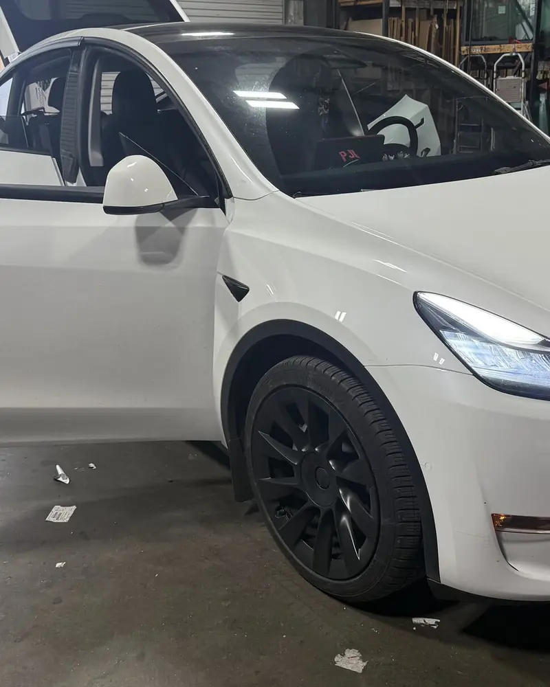 White Tesla Model Y at the Low Price Auto Glass shop with the driver door open