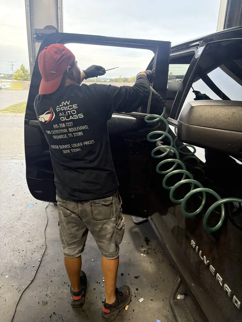 Technician cleaning broken glass from a vehicle door