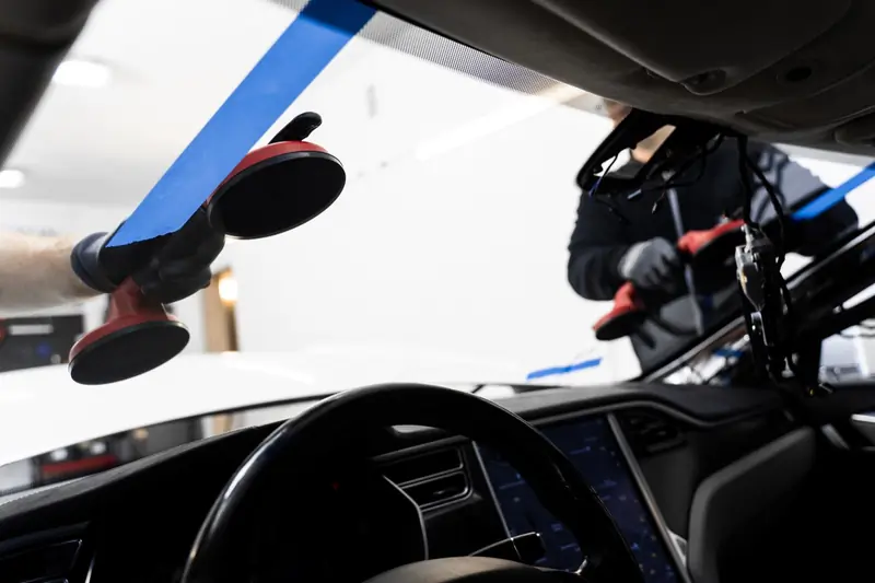 Technician replacing an automobile windshield, view from inside the vehicle